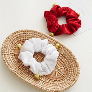 Detail of red and white velvet scrunchies with gold bells in a woven basket
