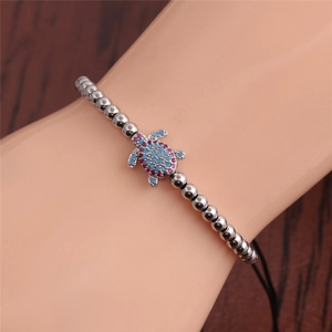 Detail view of silver turtle bracelet with pink and blue stones on adjustable black cord