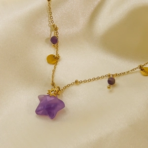 Macro detail of star pendant necklace with purple gemstone on silk fabric