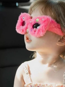 Detail of pink fuzzy sunglasses for kids featuring colorful gems and plush texture
