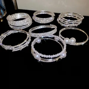 Bracciali multistrato elastici con perle sintetiche e strass scintillanti su sfondo nero