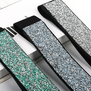 Detail of wide elastic waist belts with shimmering rhinestones in green, blue, and silver