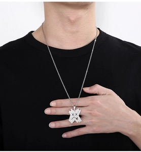 Détail du collier argenté avec pendentif visage en pleurs serti de strass brillants