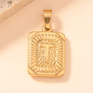 Macro detail of gold-plated square pendant with embossed letter T and hammered texture