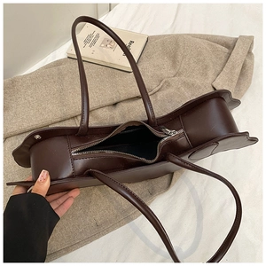 Detail view of coffee brown faux leather tote bag with unique petal edge and top zipper