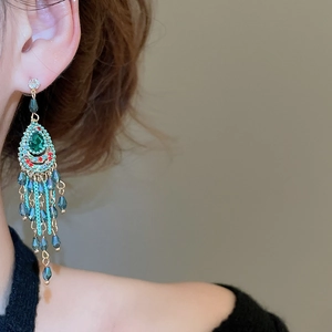 Detailed macro view of bohemian long tassel earrings with emerald green water drop gems