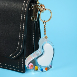 Close-up of heart-shaped acrylic charm with colorful dots on a black leather bag