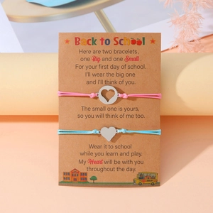 Vista dettagliata dei braccialetti intrecciati rosa e blu con ciondoli a cuore su carta