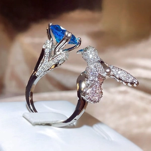 Macro detail of silver hummingbird ring with a large blue gemstone and pavé stones