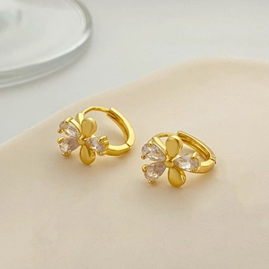 Elegant gold flower hoop earrings with zircon petals on a minimal beige display tray