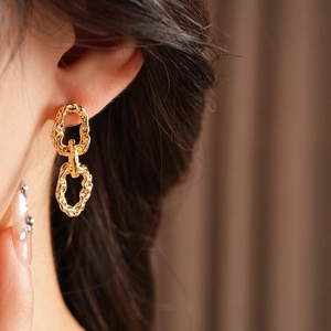 Macro de boucles d'oreilles double chaîne dorées avec texture martelée sur un mannequin