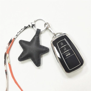 Macro detail of star-shaped leather keychain charm with a patterned ribbon on a car key