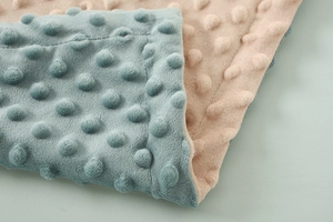 Dettaglio macro della coperta minky blu e beige con trama a pois 3D morbida