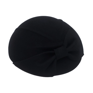 Detailed view of elegant black wool beret with oversized bow accent and textured finish