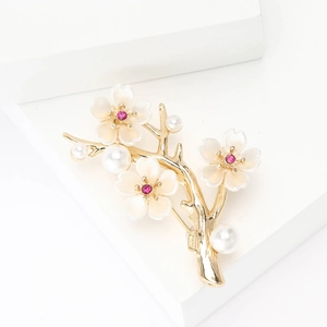 Detail of a golden cherry blossom brooch with white enamel flowers and pearls