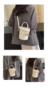 Detail of cream quilted cylinder bag with silk scarf handle and golden hardware on model