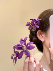 Détail de l'épingle à cheveux fleur en tissu violet avec gouttelettes et étamine dorée