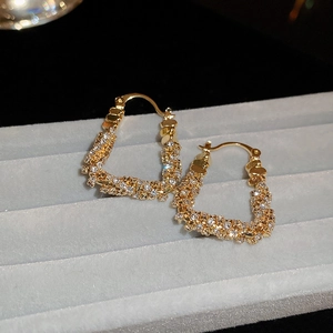 Macro shot of gold-plated U-shaped hoop earrings with sparkling zircon stones