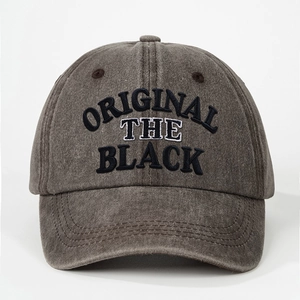 Close-up of ORIGINAL THE BLACK embroidery on a washed dark gray cotton canvas baseball cap