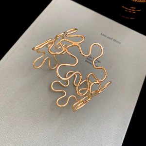 Detailed view of an open golden metal bracelet with hollow flower artistic design