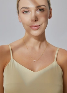 Close-up of a delicate gold cross pendant necklace with sparkling white zircons on a model