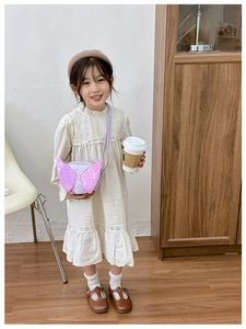 Detail view of pink sequin wing crossbody bag worn by child model with dress