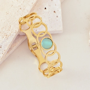 Macro view of gold chain link bracelet with polished blue cat-eye stone on stone