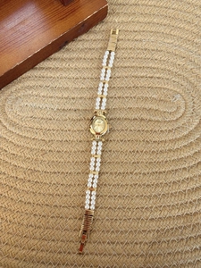 Close-up of vintage pearl bracelet watch with golden oval case and mother of pearl dial