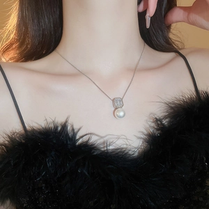 Gros plan d'un pendentif en perle blanche et zircon carré sur collier argenté