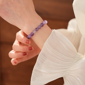 Detailansicht eines lila Amethyst-Perlenarmband am Handgelenk mit sanftem Licht am Modell