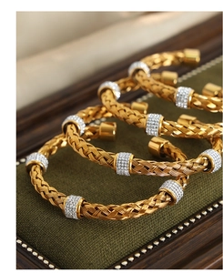 Macro view of gold woven cable bracelet with rhinestone circles in a green jewelry box