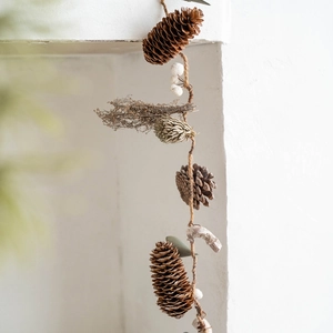 Nordic Christmas wreath with natural pine cones and white berries hanging on white wall
