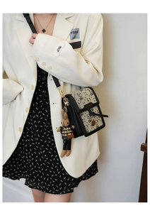 Detail of a black and beige patchwork crossbody bag with bear embroidery and rabbit charm
