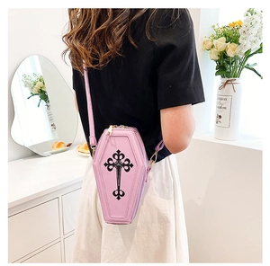 Pink coffin-shaped crossbody bag with black gothic cross shown on a female model