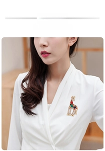 Detailed view of a colorful rhinestone giraffe brooch pinned on a white blouse