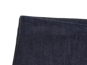 Vue détaillée des coutures et de la texture du denim bleu foncé sur un fond blanc neutre