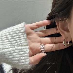 Detail view of model wearing a silver chain ring and geometric hoop earrings