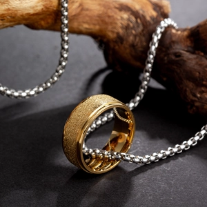 Goldener Titanstahlring mit matter Textur und passender Silberkette auf Holz