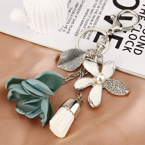 Close-up of dark green fabric flower keychain with pearls, rhinestones and silver leaf