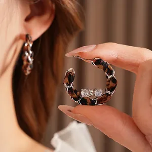 Chic woven C-shaped earrings featuring silver chain and leopard fabric with zircons
