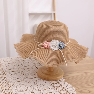 Détail d'un chapeau de paille avec fleurs pastel et ornement délicat en dentelle