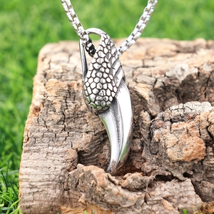 Polished silver eagle claw pendant with box chain on natural tree bark background