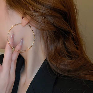 Detail view of large gold hoop earrings on a model showcasing high-shine metallic finish