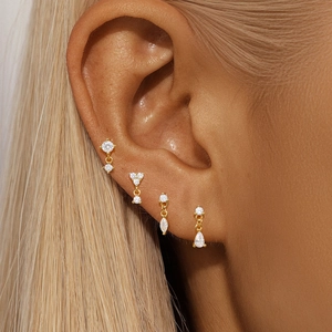 Detail of four gold S925 silver stud earrings with sparkling crystals worn on ear