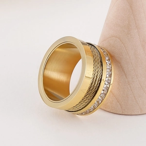 Macro detail of gold-plated titanium ring featuring Roman numerals and white rhinestones