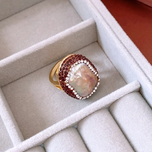 Detailed macro of 18k gold plated ring with baroque pearl and red crystals