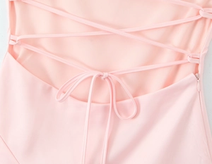Detail of pink dress featuring a crisscross back tie design and hidden side zipper closure
