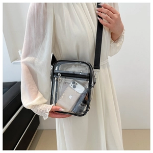 Detail view of transparent PVC crossbody bag with black trim on white pleated dress