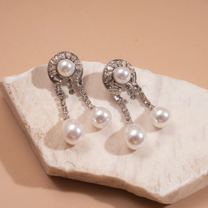 Macro view of silver geometric pearl drop earrings with sparkling rhinestones on stone