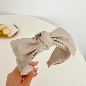 Macro detail of the beige faux leather texture and bow knot design on this headband